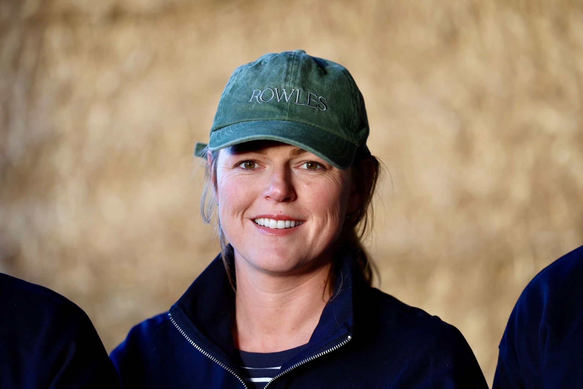 Person wearing a green cap with 'Rowles' branding against a beige background