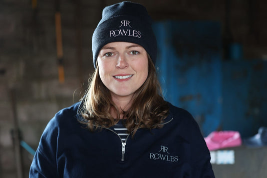 Georgie wearing a navy blue beanie and jacket with 'RR Rowles' branding in an indoor setting.