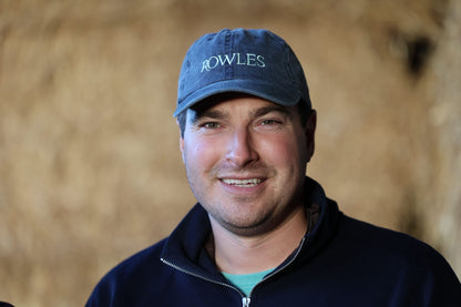 Man wearing a blue cap with 'Rowles' logo against a blurred background