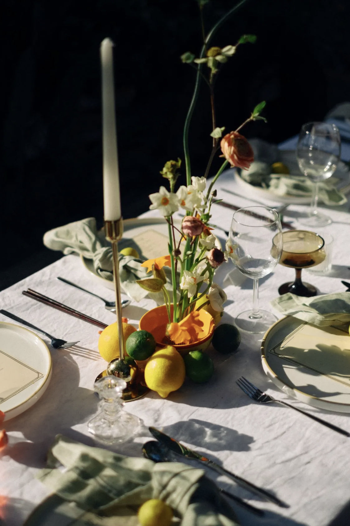 Elegant table setting with flowers, lemons, and candles on a white tablecloth.