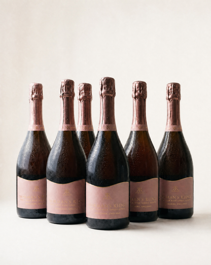 Six bottles of english sparkling rose with pink labels on a white background