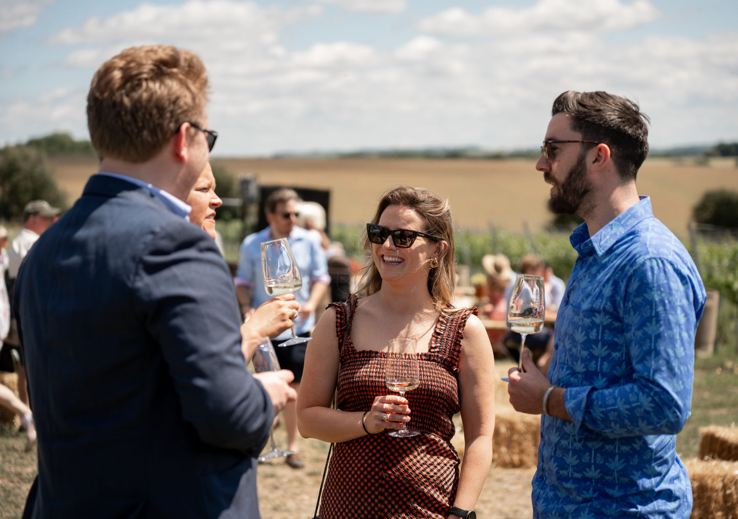 People socializing outdoors with wine glasses in a scenic setting
