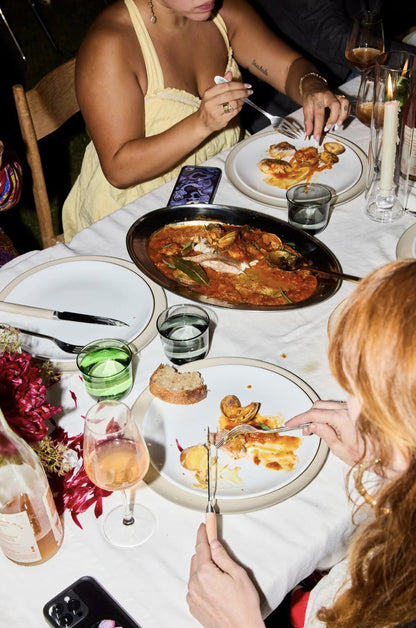 Two people dining at a table with plates of food, drinks, and cutlery.
