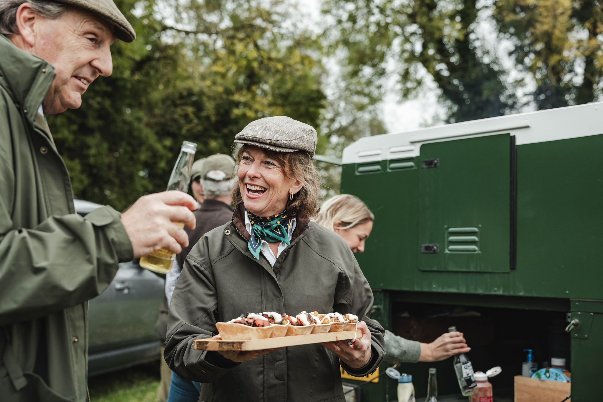 Sandra holding a tray of food, with a green vehicle in the background.