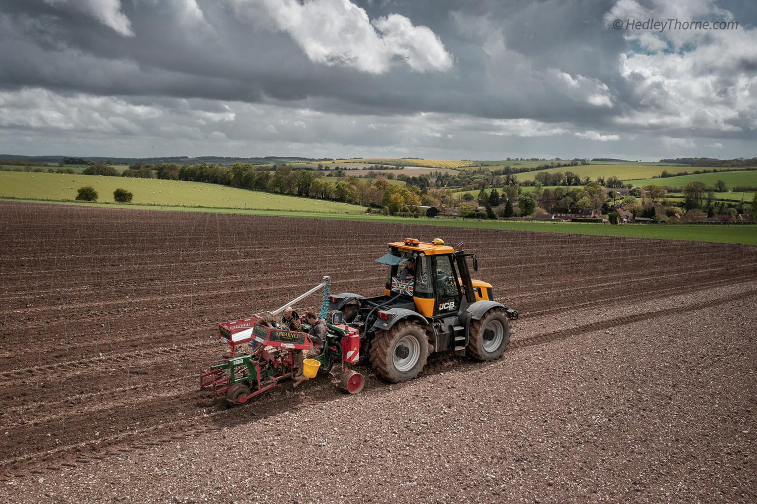 Tractor plowing a field with a cloudy sky in the background